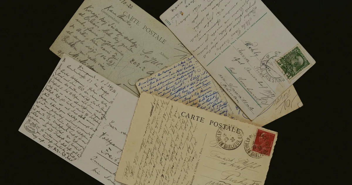 Cartes postales anciennes couvertes d’écriture à la plume, sur fond sombre