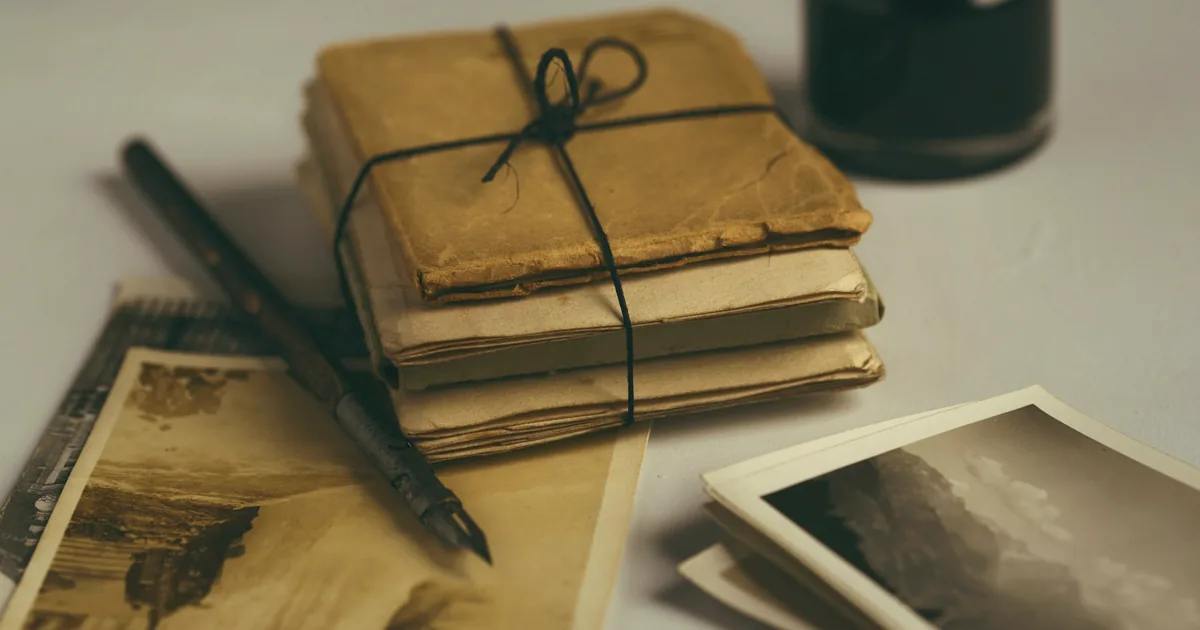 Pile de vieilles lettres nouée d’une ficelle, avec un stylo-plume et des cartes anciennes