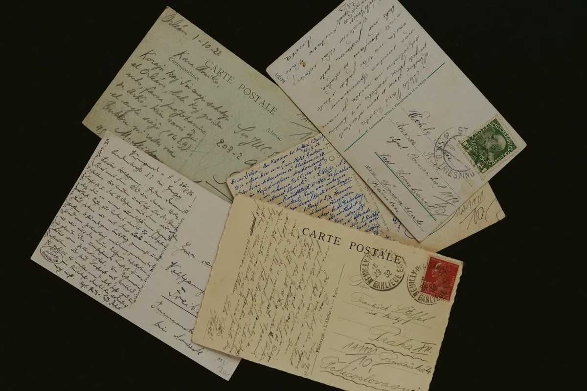 Cartes postales anciennes couvertes d’écriture à la plume, sur fond sombre